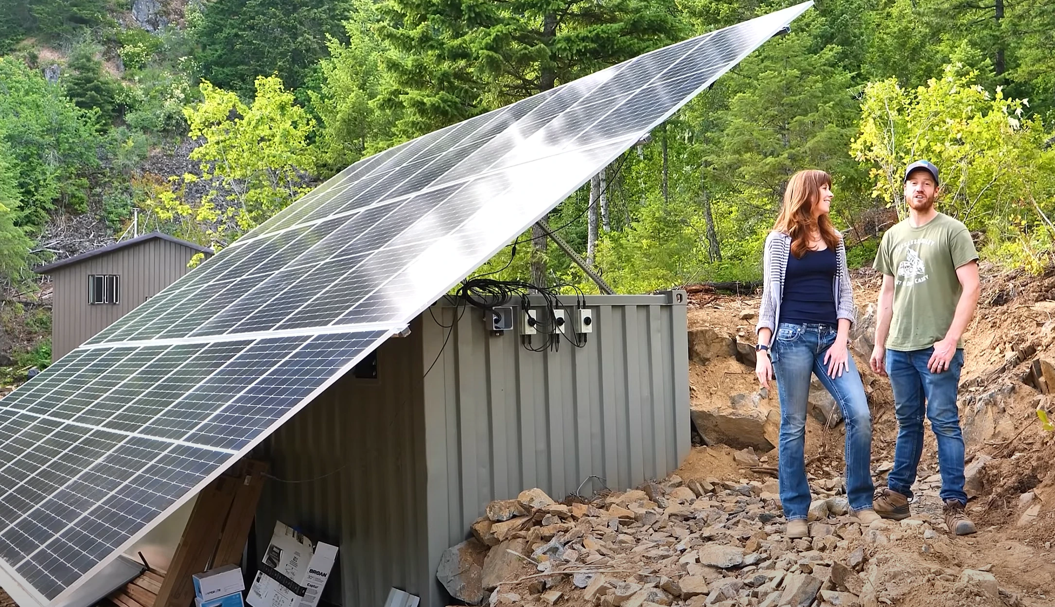 High quality photo of couple in front of their solar panel set up on their off-grid property featured in the Current Connected weekly newsletter. Photographed by Current Connected.